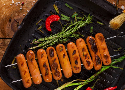 煎香肠用香草, 香料和蔬菜在平底锅。在木背景
