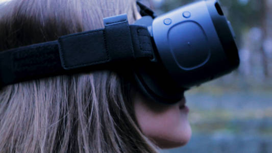 与虚拟现实技术在室外公园的美丽女人。Vr 耳机眼镜设备。年轻女子在 Vr 眼镜在公园里。特写
