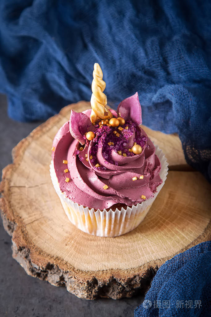 巧克力杯蛋糕加奶油以独角兽的形式孩子的生日深色背景