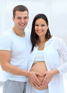 丈夫和怀孕的妻子，双手合十在他肚子上的一颗心的形状