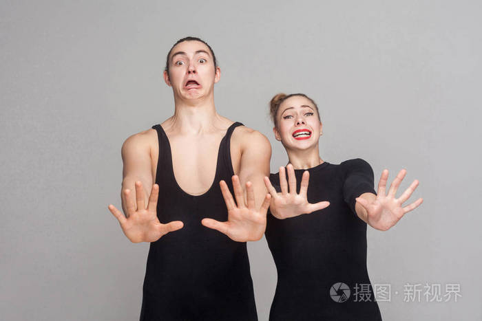 紧身的两个舞者带着恐惧和紧张的神色在他们面前用灰色的背景把手举起来