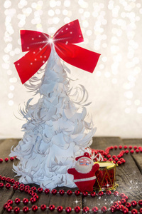 白色的折纸圣诞树, 红丝带和红色饰物在木制底座上