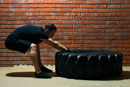 运动员 crossfit 训练用橡胶轮胎在红色背景砖