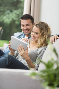 快乐的年轻夫妇在他们的平板电脑上观看互联网