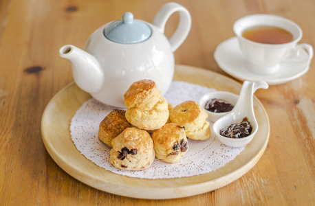 英式甜点英式早餐和茶歇, 木桌上的烤饼和一杯茶照片