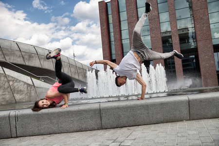 年轻的舞蹈演员夫妇跳舞嘻哈在城市背景