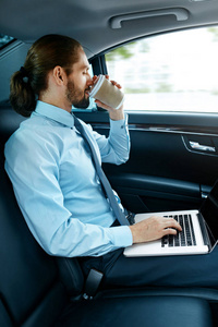 在车上工作的人在笔记本和喝咖啡