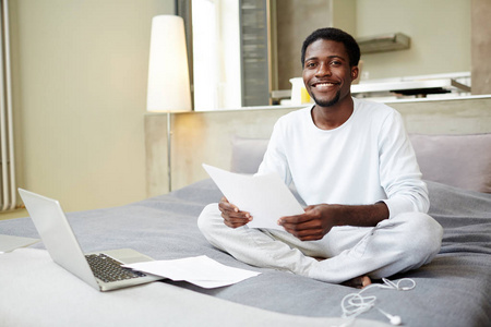 快乐的非洲裔美国企业家肖像坐在莲花位置和做文书工作时, 露微笑着看着相机