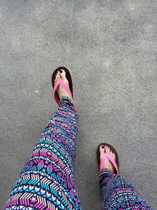 凉鞋，关闭上女孩的紫罗兰色的指甲和脚穿粉色凉鞋街头的背景上