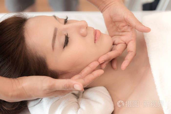 亚洲异国情调的度假水疗理念美丽的年轻中国妇女享受放松在面部按摩在