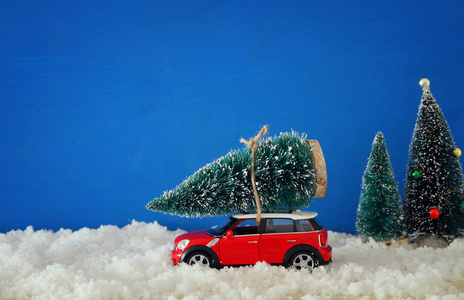 在雪地上载着一棵圣诞树的红色汽车