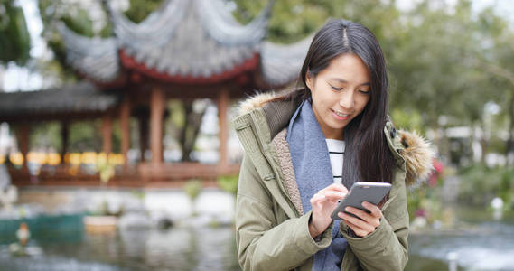 中国馆花园亚洲女子玩智能手机游戏