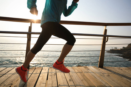 运动的健身女性赛跑者在海滨木板路上奔跑在日出