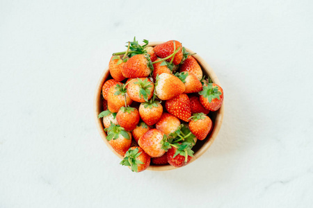 白石背景下的木碗草莓水果图片