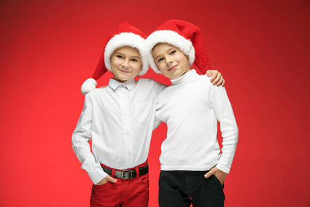 两个快乐的男孩，在圣诞老人的帽子，与在演播室的礼品盒