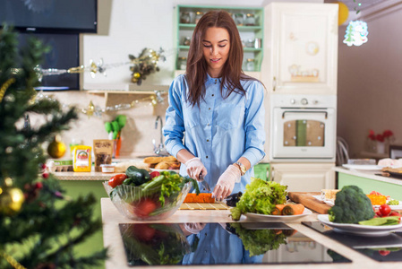 年轻的白种女人烹饪新年或圣诞大餐在家装饰厨房