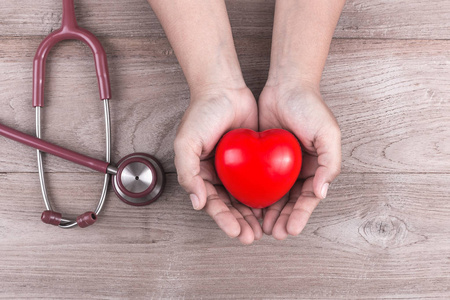 检查心脏概念: 女人手里拿着红色的心和 stethosc照片