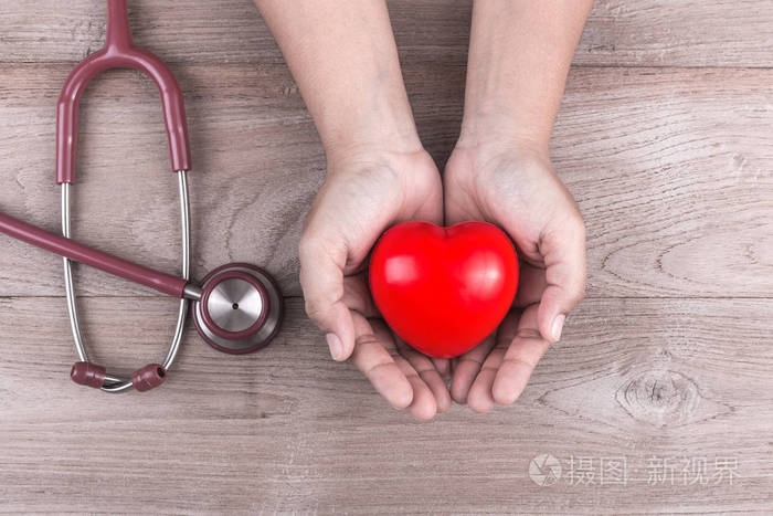 检查心脏概念女人手里拿着红色的心和stethosc
