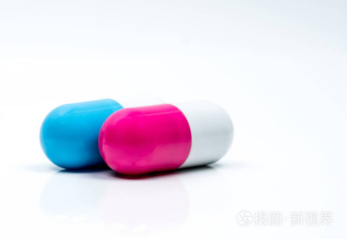 两颗胶囊药片在白色背景上分离。全球医疗保健理念