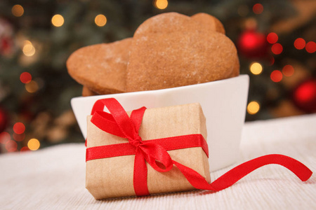 包装的礼品与红丝带 gingerbreads 和圣诞树背景灯