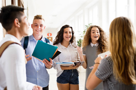 青少年学生走在高学校的礼堂里说话