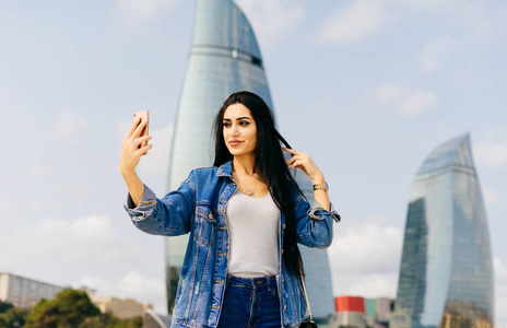 摩天大楼自拍黑发美丽的女孩穿越阿塞拜疆, 使自拍在现代建筑的背景下