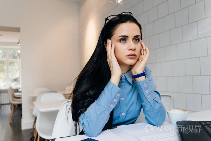 疲倦的年轻女孩自由职业者工作了很多, 头疼, 坐在咖啡馆