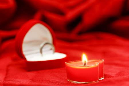 红绸背景下的一支心形蜡烛