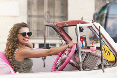 美丽的妇女游客驾驶一辆老爷车在古巴
