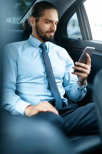 年轻的成功男子在手机上工作坐在汽车