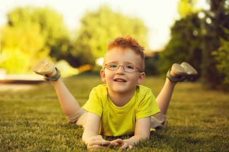 快乐宝贝男孩在草地上眼镜的红头发