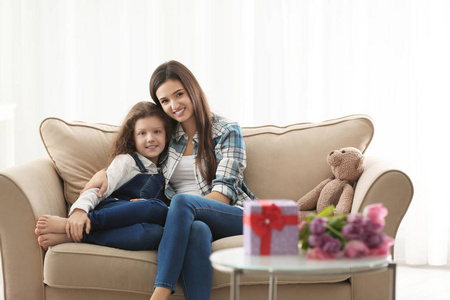 年轻的母亲和她的女儿在沙发上拥抱室内