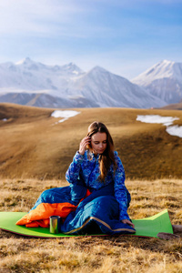 年轻的女孩, 游客, 坐在一个睡袋里的背景下, 白雪皑皑的高加索山脉