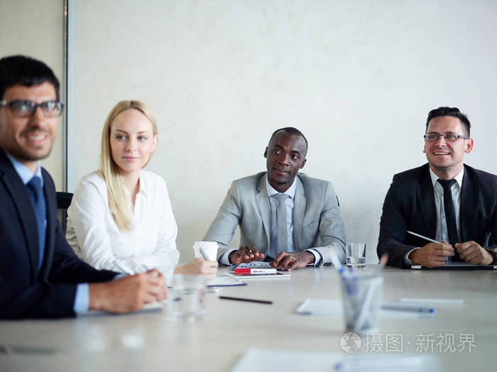 多族裔商务人士会议在会议室: 非裔美国人坐在餐桌旁与同事和微笑照片