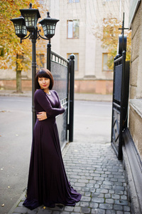 成人的黑发女人，在紫罗兰色的礼服背景黑色铁闸