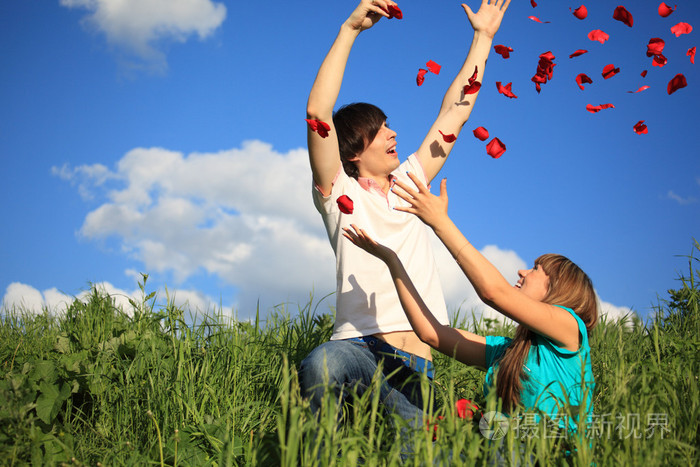 年轻的一对把玫瑰花瓣撒在草地上照片-正版商用图片03r81a-摄图新视界