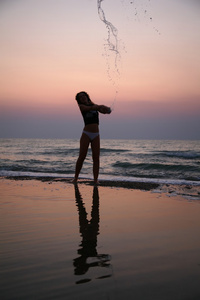 日落时分，年轻女子在海滩上撒满了水