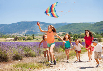 一大群年龄不同的孩子们在夏天玩彩虹风筝的乐趣