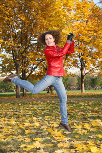 穿红色夹克的女孩秋天在公园里跳