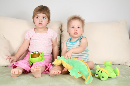 两个带玩具的孩子在沙发上