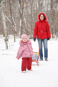 冬天有雪橇的孩子和公园里的妈妈