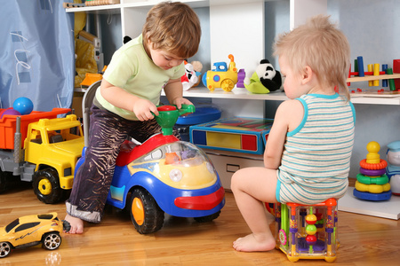 两个带玩具滑板车的儿童在游戏室