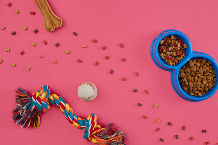 玩具多色绳, 球, 干食品和骨。在粉红色背景顶部观看的游戏配件