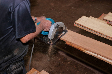 电圆锯的鸟瞰在木工车间的高级木匠手上切一块木头