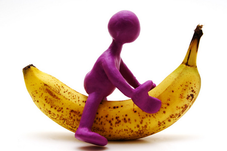 在香蕉上骑橡皮泥的紫色木偶