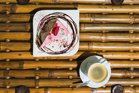 把蛋糕和咖啡杯放在竹桌上。视图