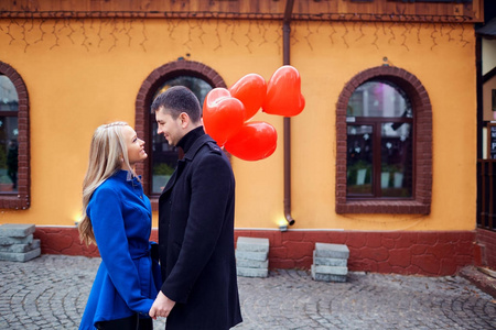 一对爱的情侣在大衣与气球的心在手上的 cit