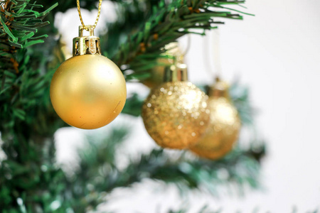 白色背景绿色圣诞树上的金色装饰球