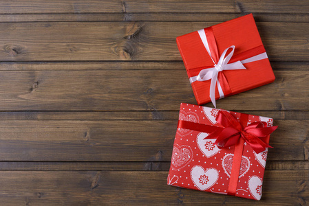两个红色的礼物盒在棕色木背景的心