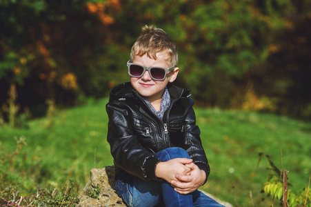肖像的男孩在秋天公园在阳光明媚的一天，一个小男孩模型构成的摄影师